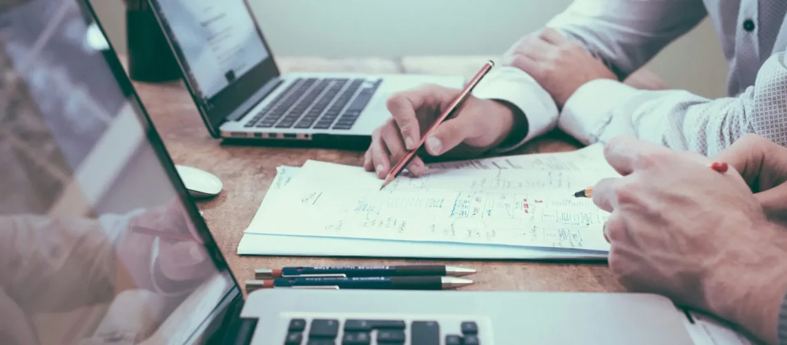 person holding a pencil near laptop